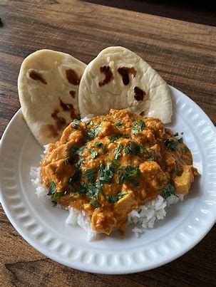 A plate of rice topped with butter chicken and a side of garlic naan. Image from https://www.reddit.com/r/food/comments/ky8qrn/homemade_butter_chicken_with_garlic_naan/