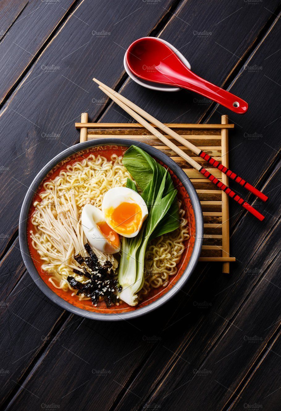 An authentic bowl of ramen with an egg on top. Next to the bowl are chopsticks and a soup spoon. Image from @creative market on Pinterest.