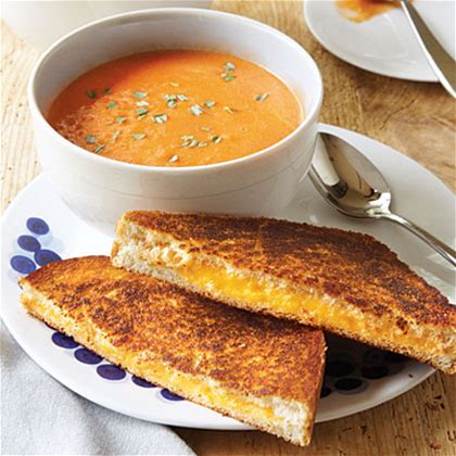 A bowl of tomato soup and basil with a diagonally sliced grilled cheese. Image from myrecipes.com